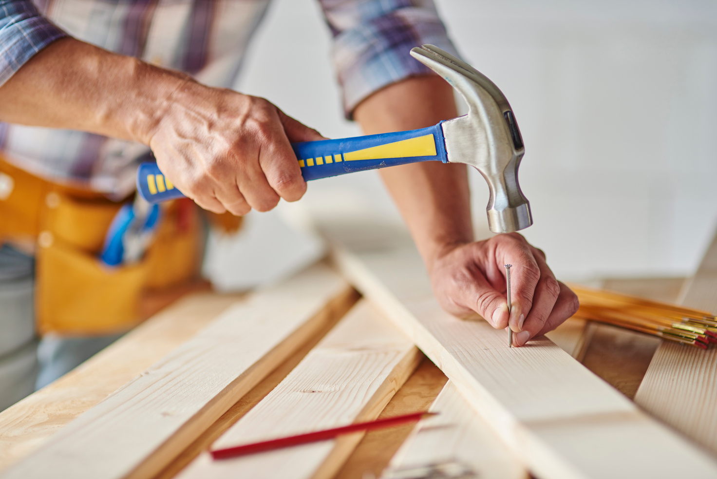 Carpenter with hammer hitting nails.