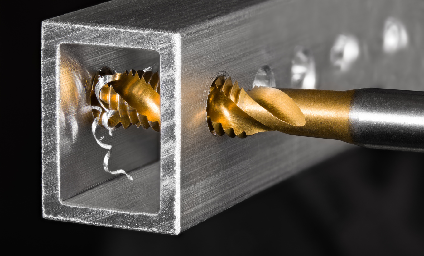 Tapping tool. Steel tap drill coated by titanium. Spiral aluminium swarf. Chip machining detail