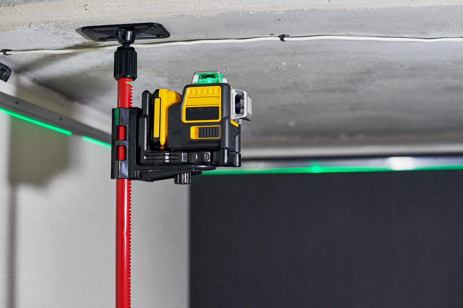 Laser Level Measuring Tool with Visible Green Laser Beam on Wall of Unfinished Apartment