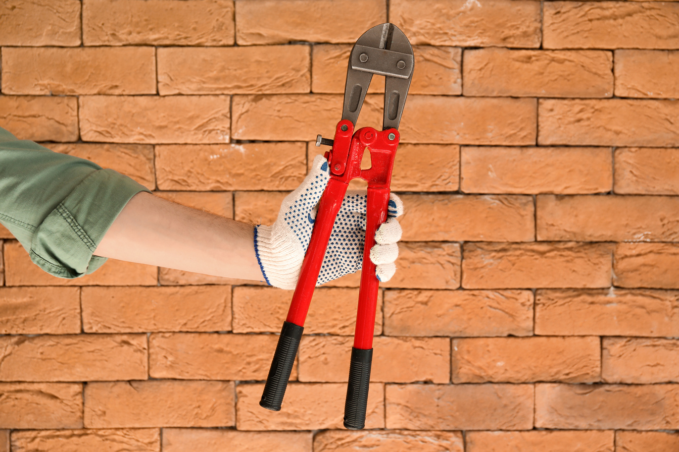 Worker with Bolt Cutter on Brick Background